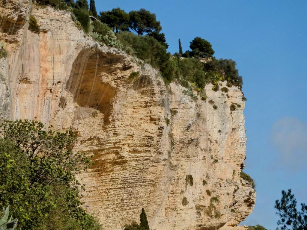 Vista de un acantilado con la Ermita de Sant Honorat en la parte superior y cielo azul de fondo.
