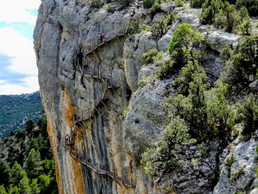 Pasarelas de madera en el desfiladero de Mont-Rebei, conectando escarpadas paredes rocosas con vistas al bosque circundante.