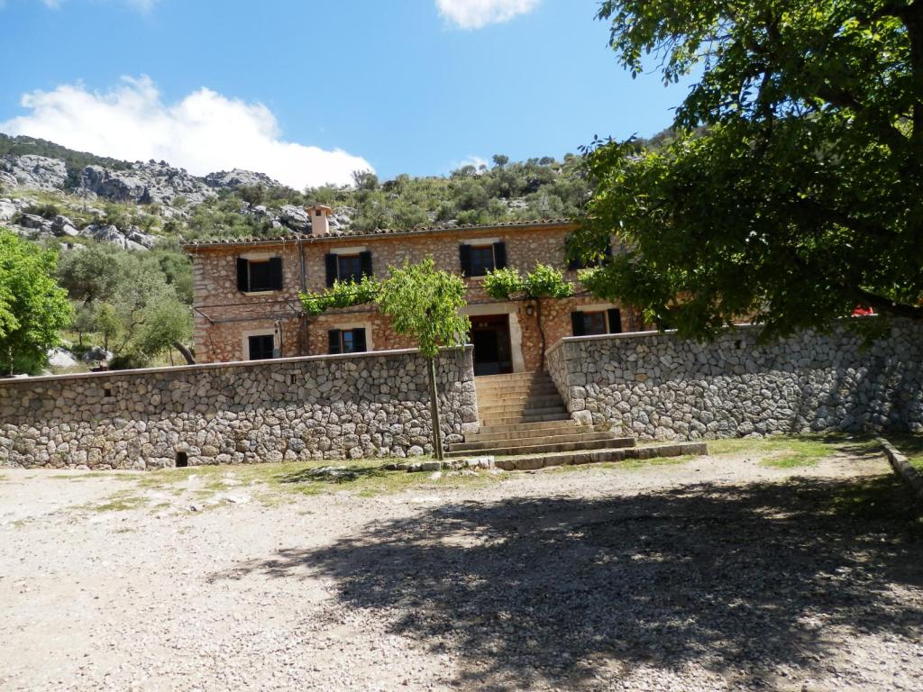 Refugio de Tossal Verds, rodeada de vegetación y montañas en el fondo.