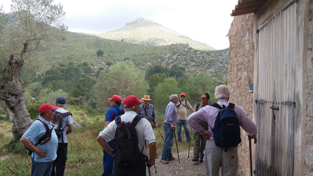 Grupo de excursionistas en la ruta 'CASAS DE GALATZÓ', con montañas y vegetación de fondo.