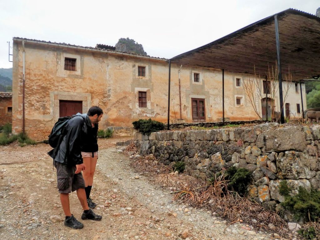 Persona mirando el suelo en un camino de tierra frente a Casas de Can Bajoca en la ruta 'CANALETA DE MASSANELLA' en Mallorca.