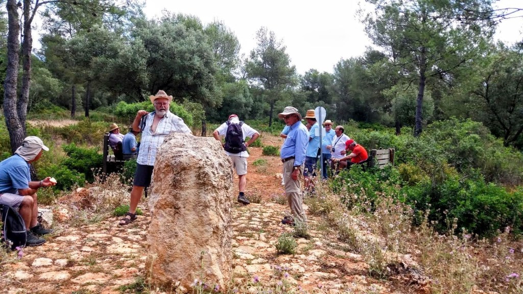 Grupo de personas en un sendero rodeado de vegetación, junto a un monolito que marca el centro geográfico de Mallorca.