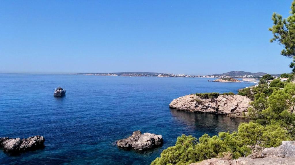 Vista panorámica de la Punta Bufador con un mar azul y una embarcación navegando en el horizonte, rodeada de rocas y un paisaje costero en calma.