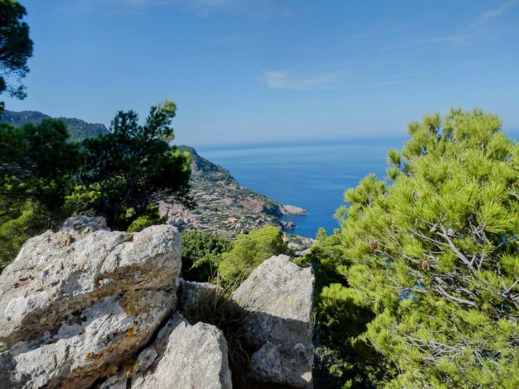Vista panorámica del mar y la costa desde Penyal de s'Heura en la ruta Puig de ses Planes-Cova de la Bernarda, rodeada de pinos y roca.