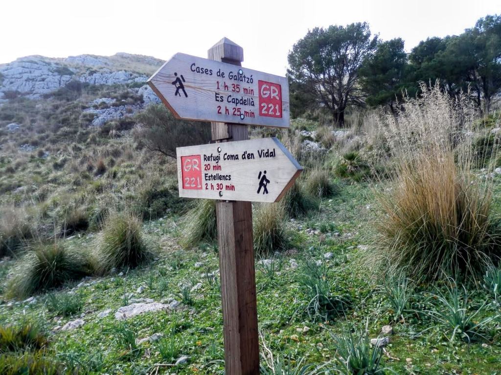 Señalización de rutas senderistas en la Mola de s'Esclop, indicando los tiempos de camino hacia Casas de Galatzó y Refugi Coma den Vidal, en un entorno natural montañoso.