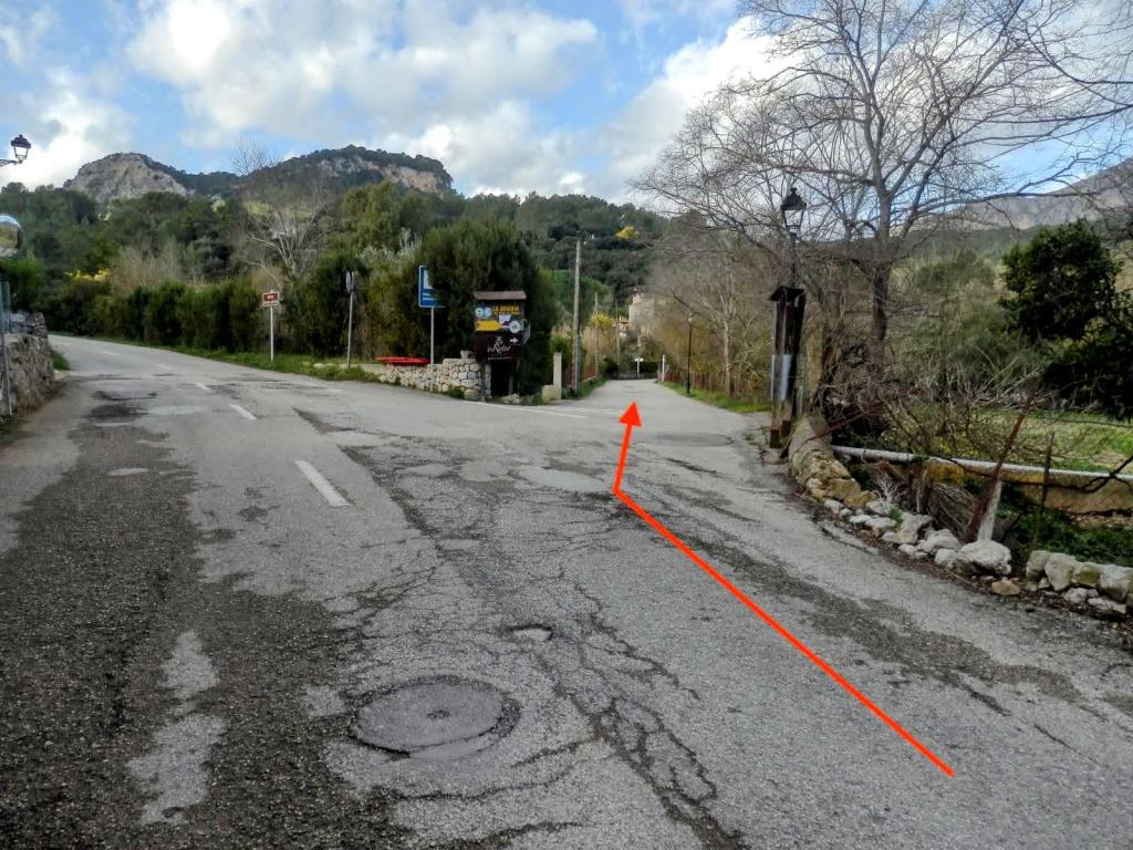 Imagen de un camino en Puigpunyent, Mallorca, donde se observa una bifurcación de vías, señales de tráfico y un paisaje montañoso al fondo.
