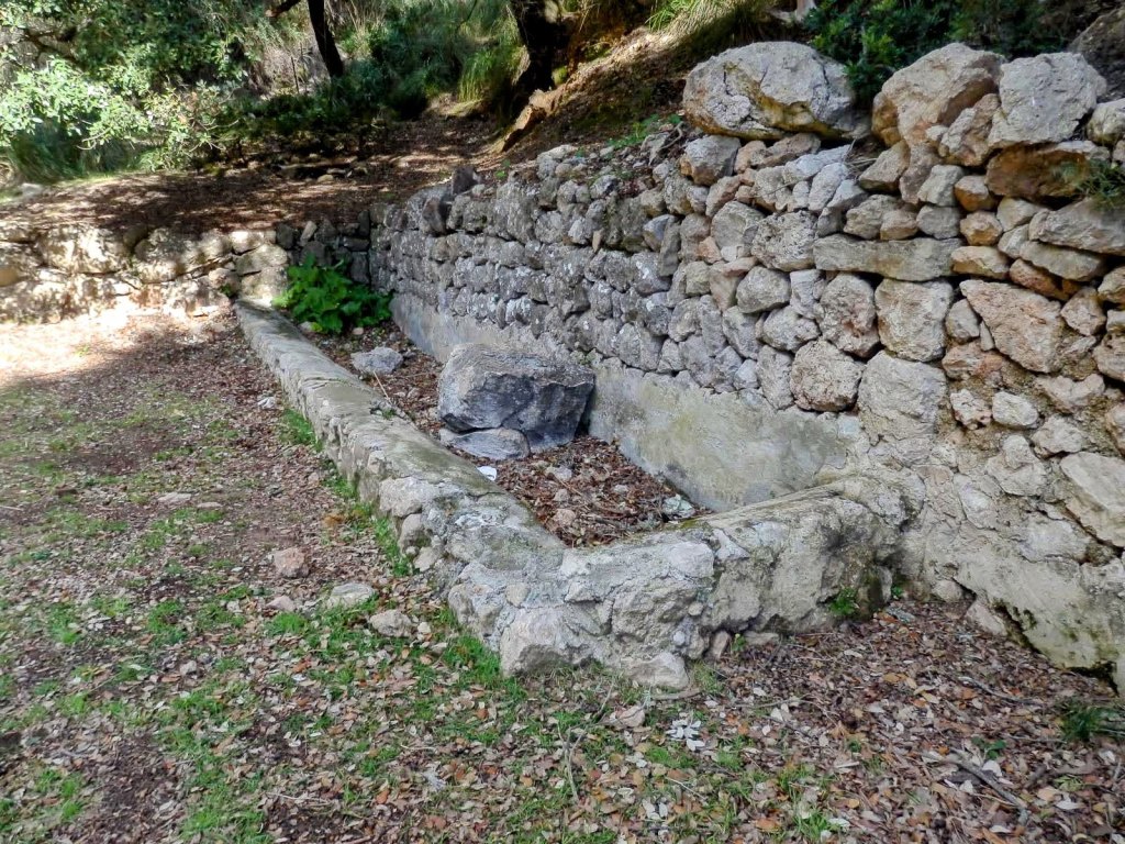 Font des Pi, una fuente de piedra seca rodeada de vegetación en la ruta hacia Puig de Galatzó desde Puigpunyent.