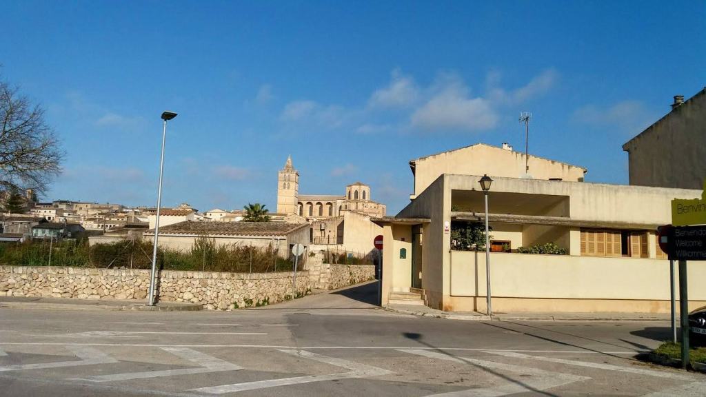 Vista del pueblo de Sineu con edificios y la iglesia al fondo bajo un cielo azul.