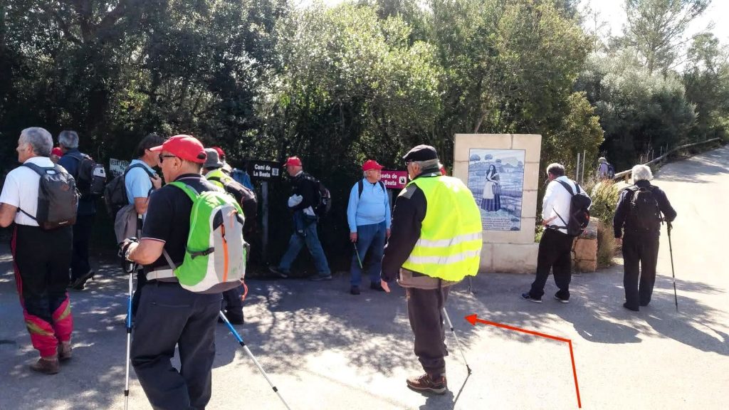 Grupo de excursionistas en el Camino de la Beata, con un cartel informativo al fondo.