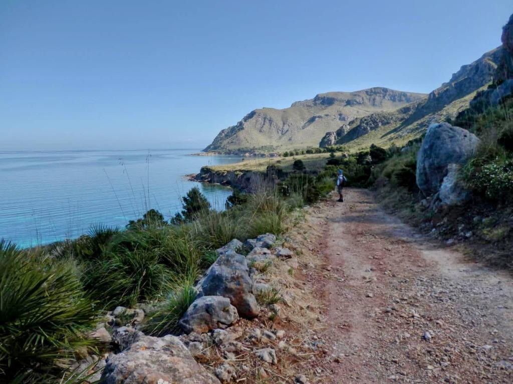 Camí d’es Caló con vistas al mar y montañas, con un caminante en la ruta Talaia Moreia.