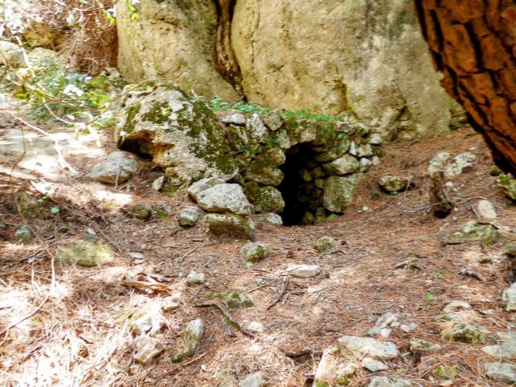 Entrada de la Font d'en Tesa en un entorno natural, rodeada de rocas y vegetación, probablemente un antiguo horno de cal.