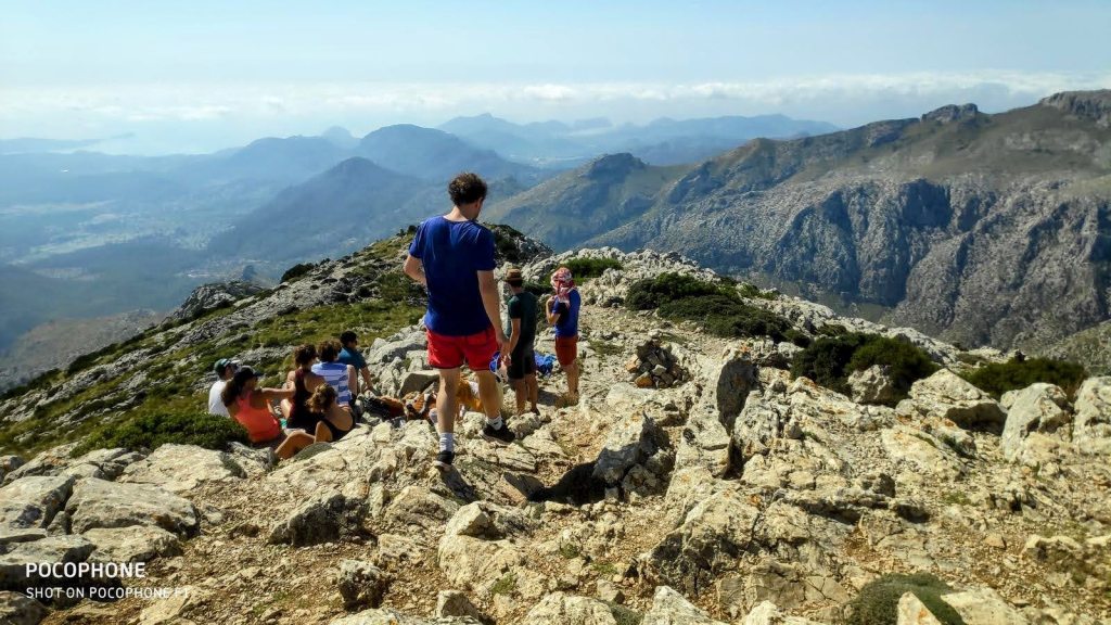 Grupo de senderistas en la cima del Puig de Galatzó, rodeados de rocas y disfrutando de las vistas de la Serra de Tramuntana.