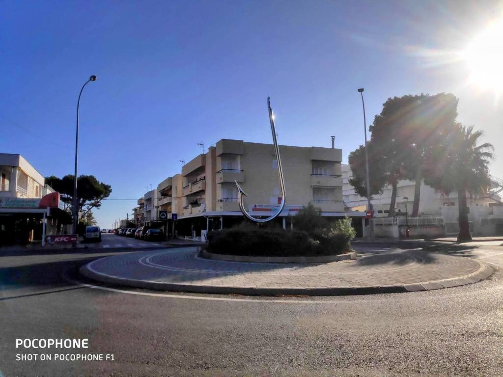 Rotonda en el Puerto de Alcudia con un gran anzuelo como centro y edificios al fondo bajo un cielo despejado.
