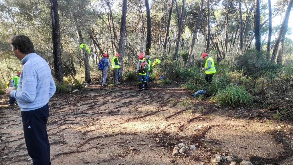 Grupo de personas con chalecos reflectantes en la Colina Putxet de Cau, preparándose para una ruta de senderismo.