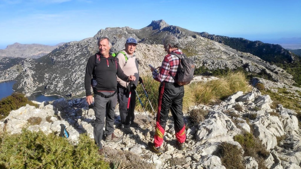Tres senderistas en la cima Puig de Sa Font, disfrutando de las vistas panorámicas del paisaje rocoso y montañoso en la Ruta Los Cuatro Tresmiles.