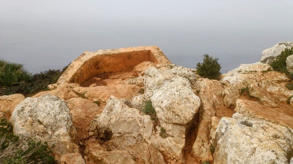 Vista del Mirador d’en Josep Sastre, rodeado de rocas y vegetación, con un ambiente nublado.
