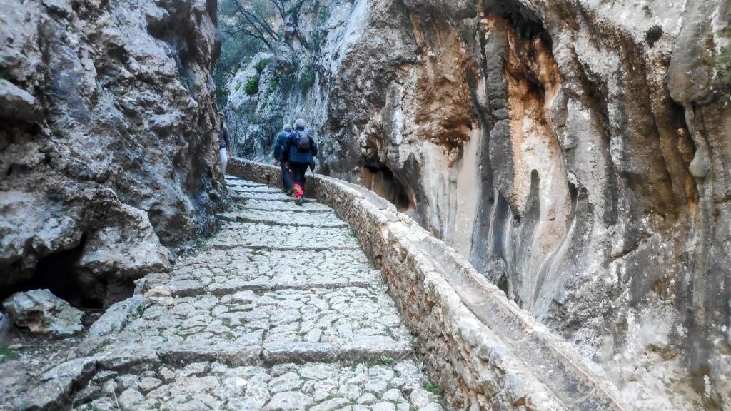 S’Estret, sendero empedrado en el Barranc de Biniaraix, con paredes rocosas a los lados y una persona caminando por el camino.