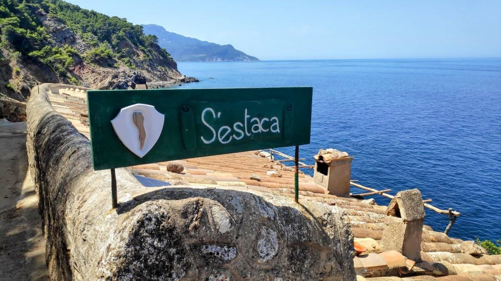 Señal indicativa de S'Estaca con fondo del mar y montañas al fondo.