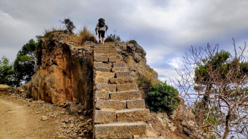 Senderista subiendo por una escalera de piedra en el Mirador des Rotlo Gros