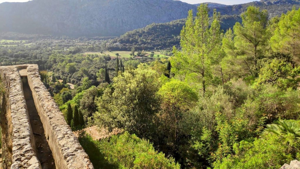 Vista panorámica del valle con vegetación exuberante y montañas al fondo, observada desde un Molins de Llinars.
