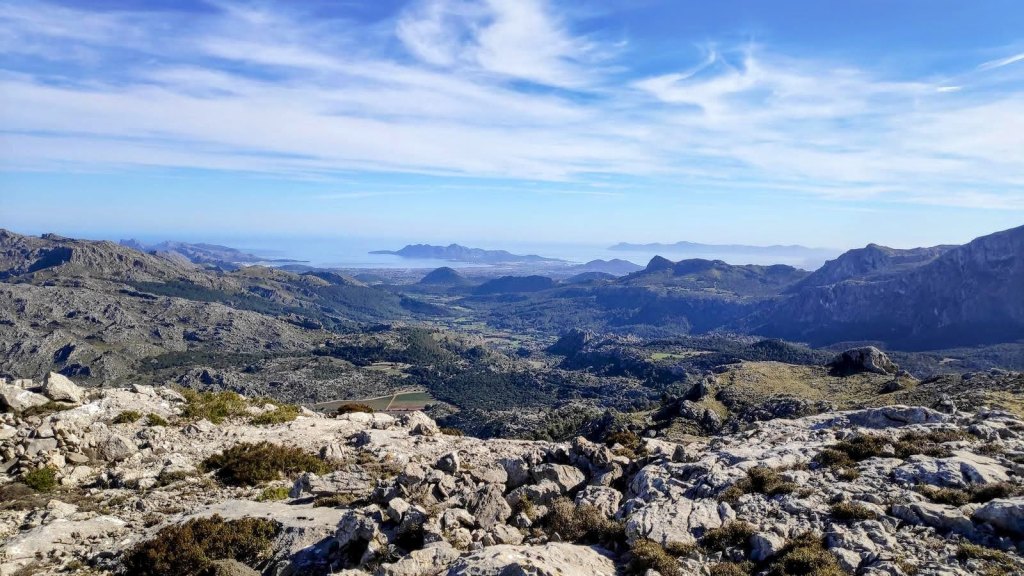 Vista panorámica desde la cima del Puig Caragoler, mostrando montañas y el valle circundante con vegetación y un cielo despejado.