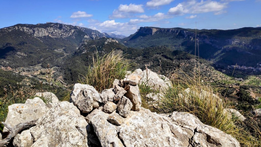 Vista panorámica desde la cima del Puig de Son Nassi, mostrando un paisaje montañoso con colinas y valles cubiertos de vegetación y rocas.