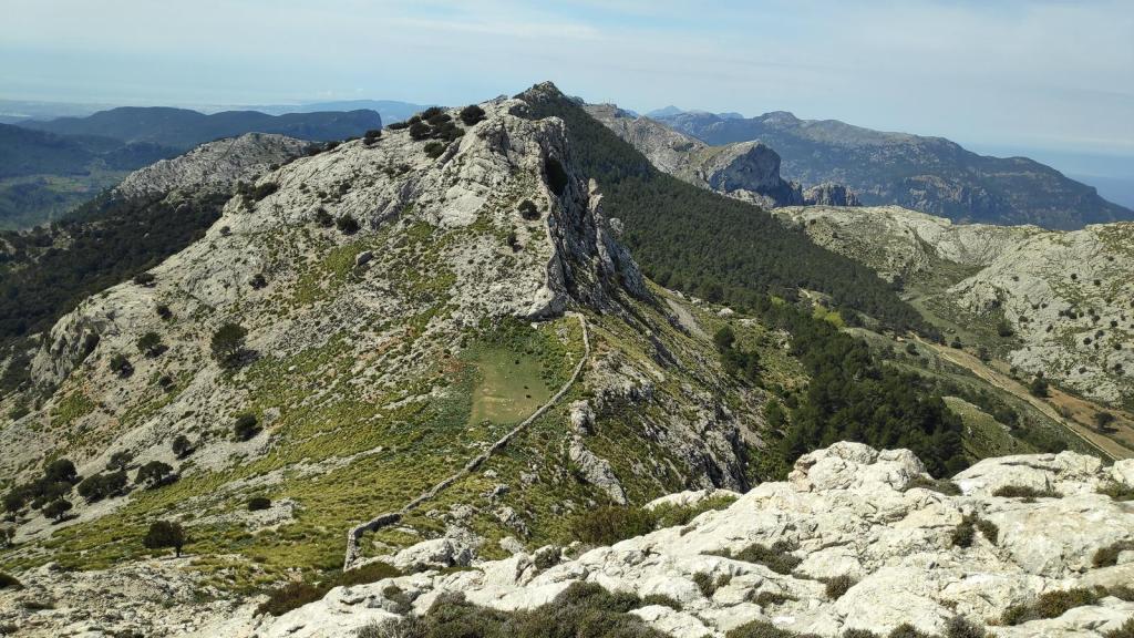 Panorámica de la ruta Los Tres Miles desde Cúber, mostrando el Coll dels Gats con un fondo de vegetación y un cielo despejado.