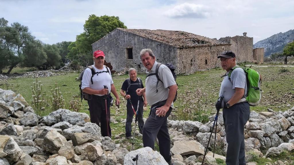 Cuatro senderistas en un paisaje montañoso cerca de las  Casas de Fartàritx, con rocas y vegetación alrededor.