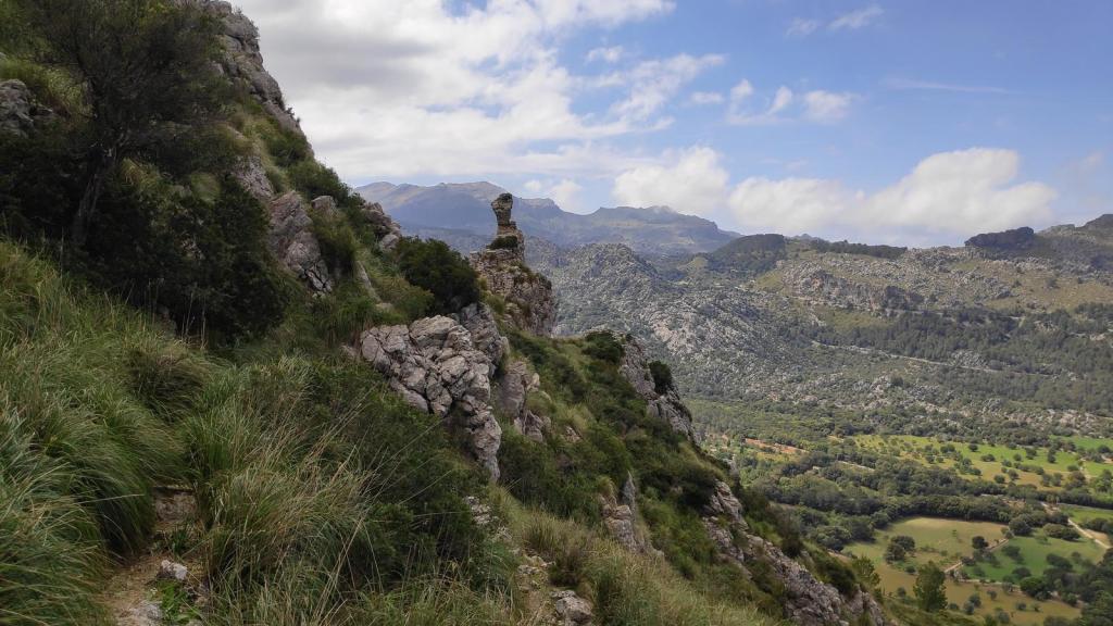 Vista panorámica de la montaña y el Ninot, con rocas y vegetación, y un fondo de paisajes montañosos y valles verdes.