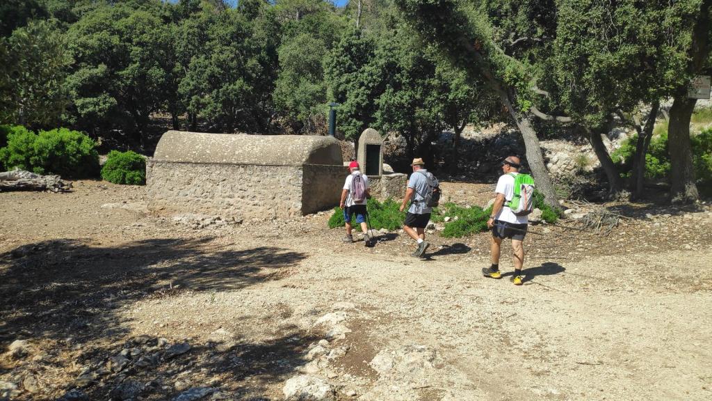 Grupo de excursionistas caminando hacia el Aljibe de Mestre Pericó Barbut en medio del bosque.