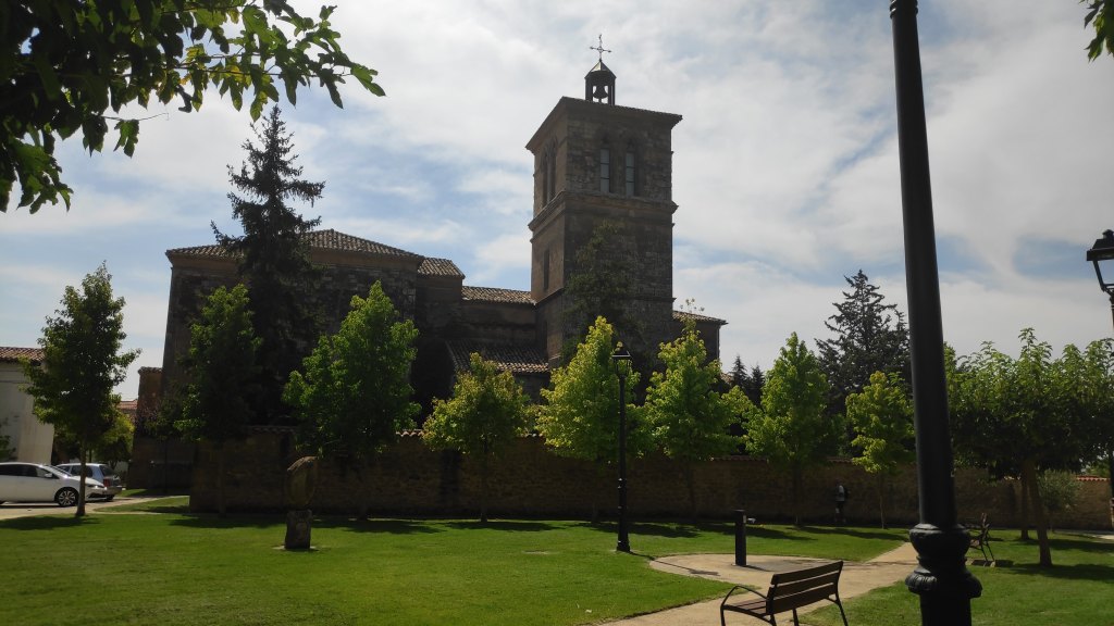 iglesia gótica de San Esteban  con campanario y entorno ajardinado en un parque, rodeada de árboles y un espacio verde.