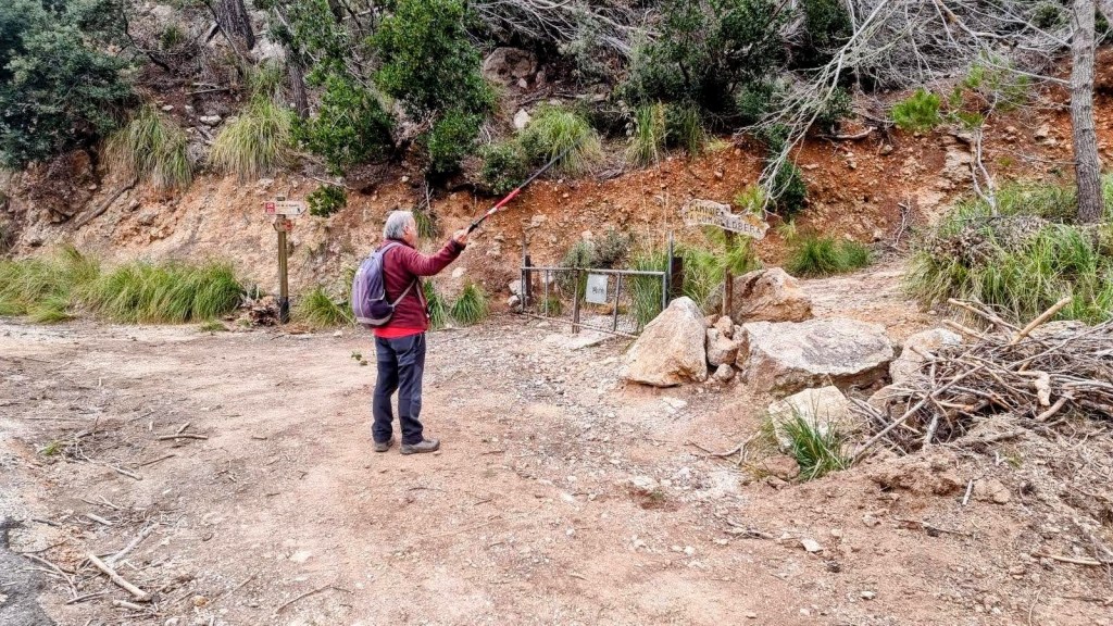Senderista en un camino de tierra junto a señales del sendero, señalando el Camí de sa Coma Llobera