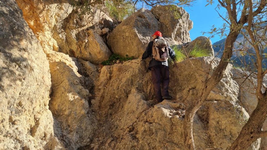 Una persona escalando por el Pas de sa Cova, con un paisaje montañoso visible al fondo.