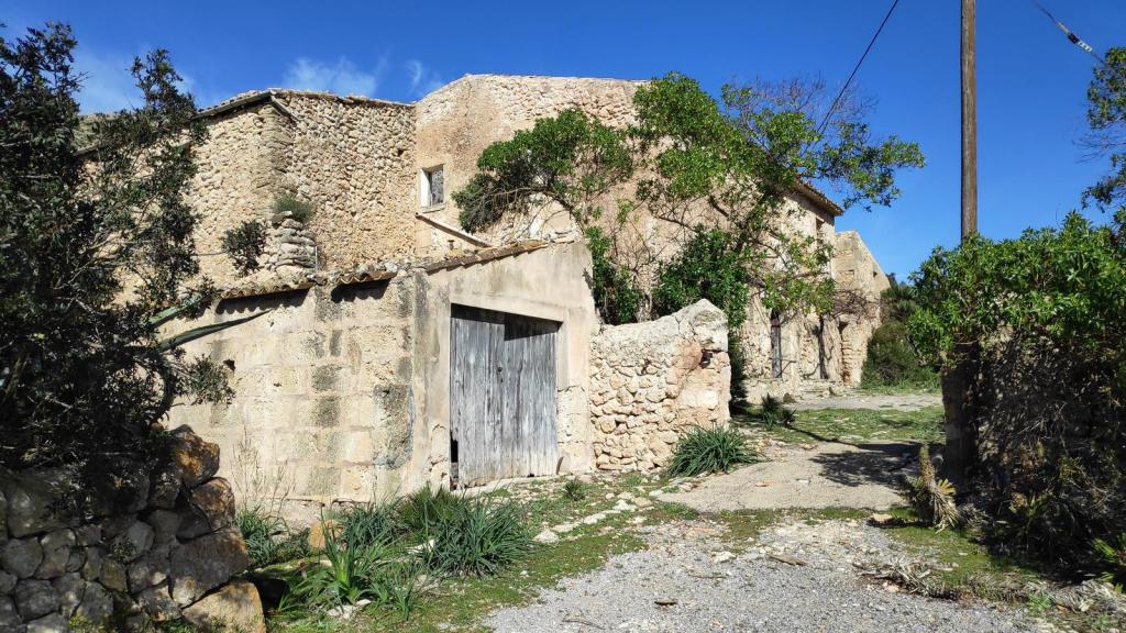 Vista de una antigua edificación de piedra con vegetación alrededor, ubicada en la Ruta de la Pedra en Sec, GR221, en Mallorca.