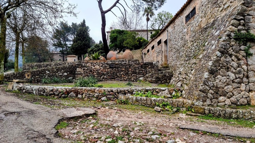 Vista de las Casas de Solleric.  con paredes de piedra, rodeada de árboles y vegetación, en una ruta de senderismo cerca de Alaró.