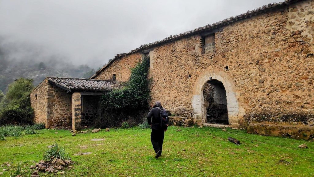 Persona caminando hacia las casas de Olí Clarc on un ambiente rural y nublado.
