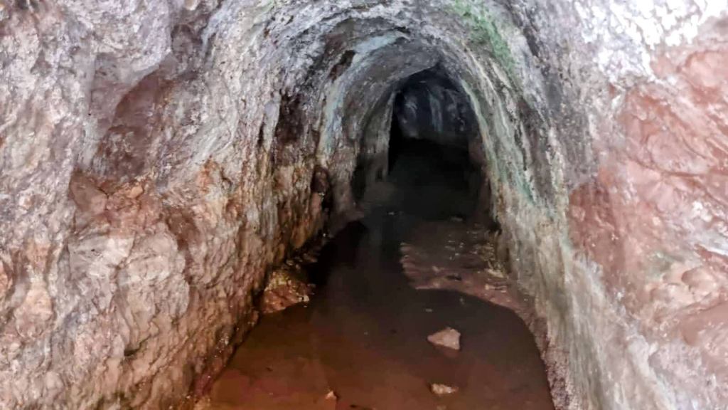 Mirador de les Barques desde el Puerto de Sóller - Caminando por Mallorca Interior de la Font des Moro o Font Roja, con paredes de roca y agua estancada en el suelo.