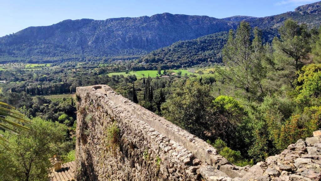 Puig Gros de Ternelles 2 - Caminando por Mallorca Vista panorámica desde Molins de Llinars, mostrando un paisaje montañoso y verde con árboles y campos al fondo.