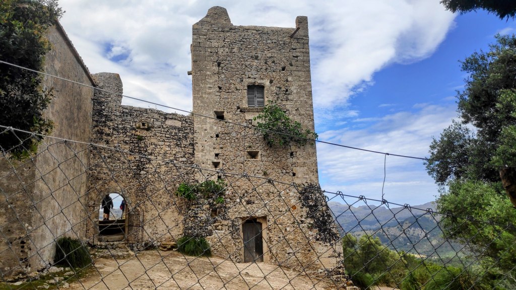 Vista del edificio de la Torre de Defensa en Puig de María, con una estructura de piedra y un entorno natural montañoso, bajo un cielo nublado.