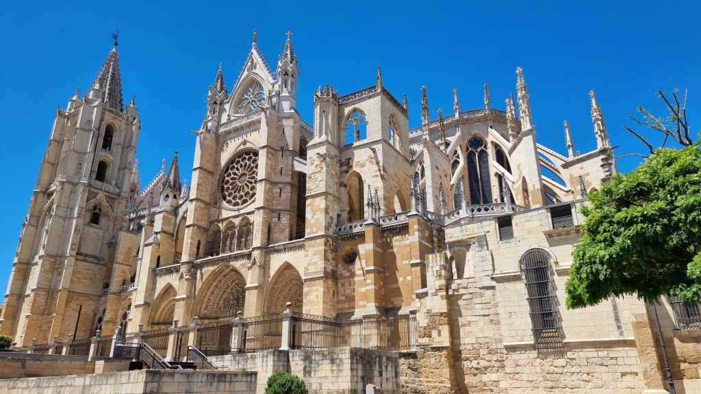 Vista de la Catedral de León, con su arquitectura gótica, torres y detalles ornamentales, bajo un cielo azul despejado.