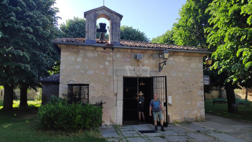 Ermita de San Amaro, rodeada de árboles en un parque, con personas saliendo por la puerta.