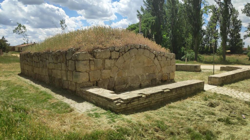 Etapa 15:Castrojeriz-Frómista - Caminando por Mallorca Ruinas de una estructura de piedra cubierta de hierba, rodeada de un área verde con senderos y árboles, ubicada en un paisaje rural.