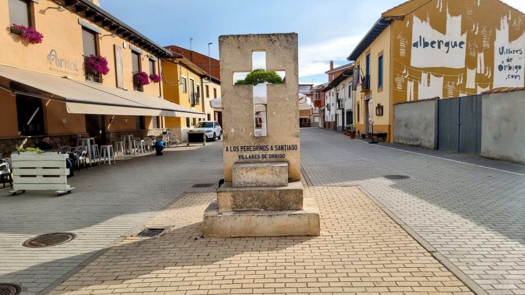 Etapa 22:San Martín del Camino-Astorga - Caminando por Mallorca Monumento en Villares de Órbigo dedicado a los peregrinos del Camino de Santiago, con un diseño sencillo y un entorno urbano.