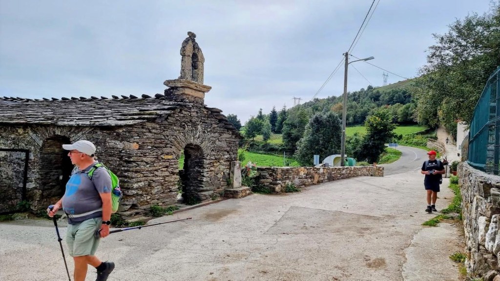 Dos peregrinos caminan por un camino rural en Galicia, cerca de la Ermita dedicada a San Pedro en O Biduedo