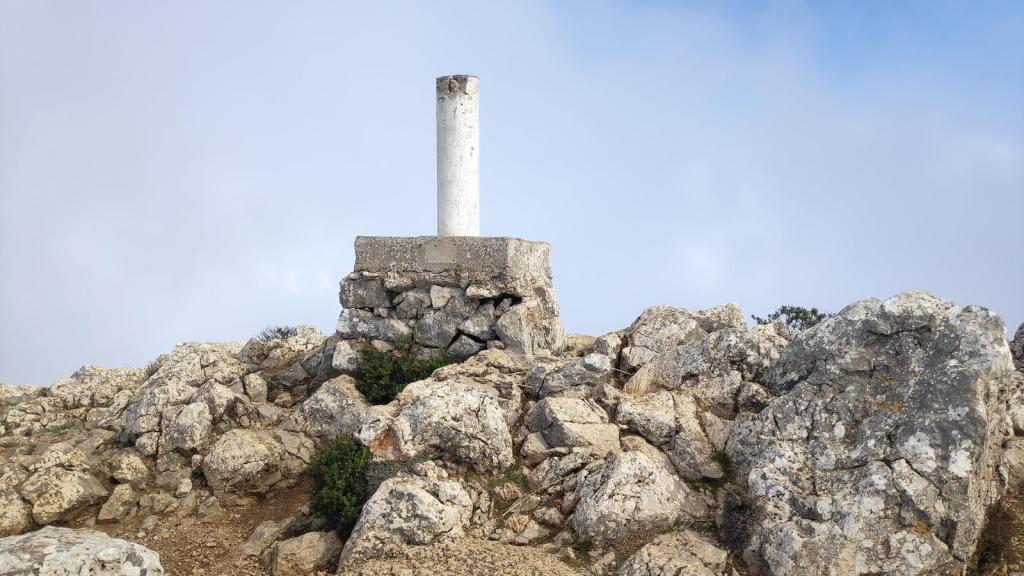 Vértice geodésico en la cima del Puig de Galatzó, rodeado de rocas en un paisaje montañoso.