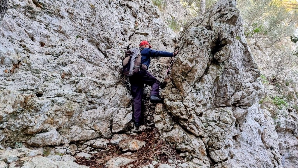 Un senderista trepando por el Pas de sa Ventalla