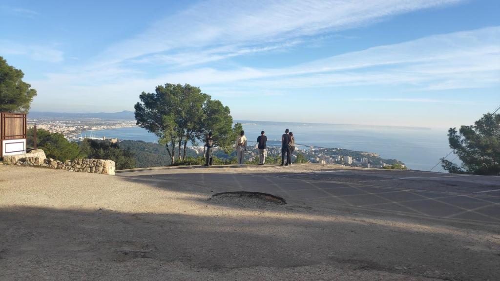 Personas observando el paisaje desde un mirador en la Serra de Na Burguesa, con vistas a la bahía de Palma y alrededores.