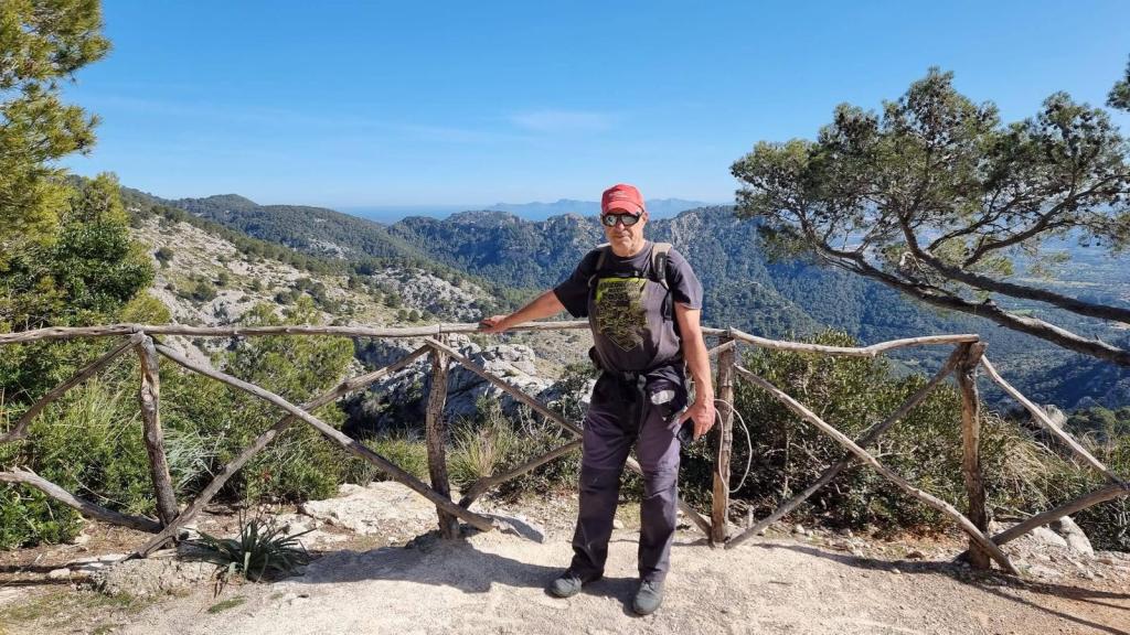 Persona de pie en el jMirador de “sa Llangonissa”, con un paisaje montañoso y un cielo despejado como fondo.