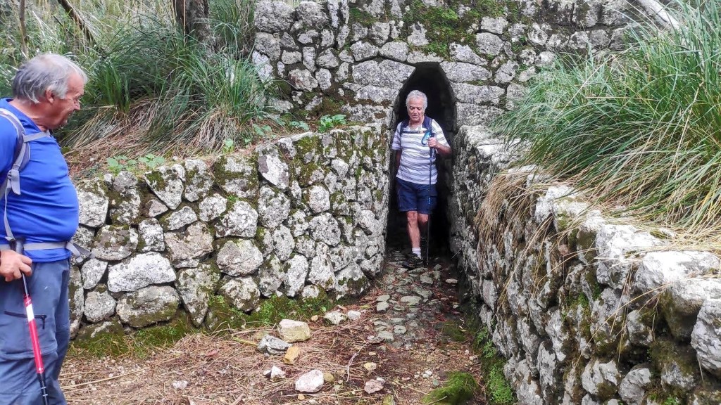 Dos personas caminando a través del estrecho pasadizo de la Font de sa Mina