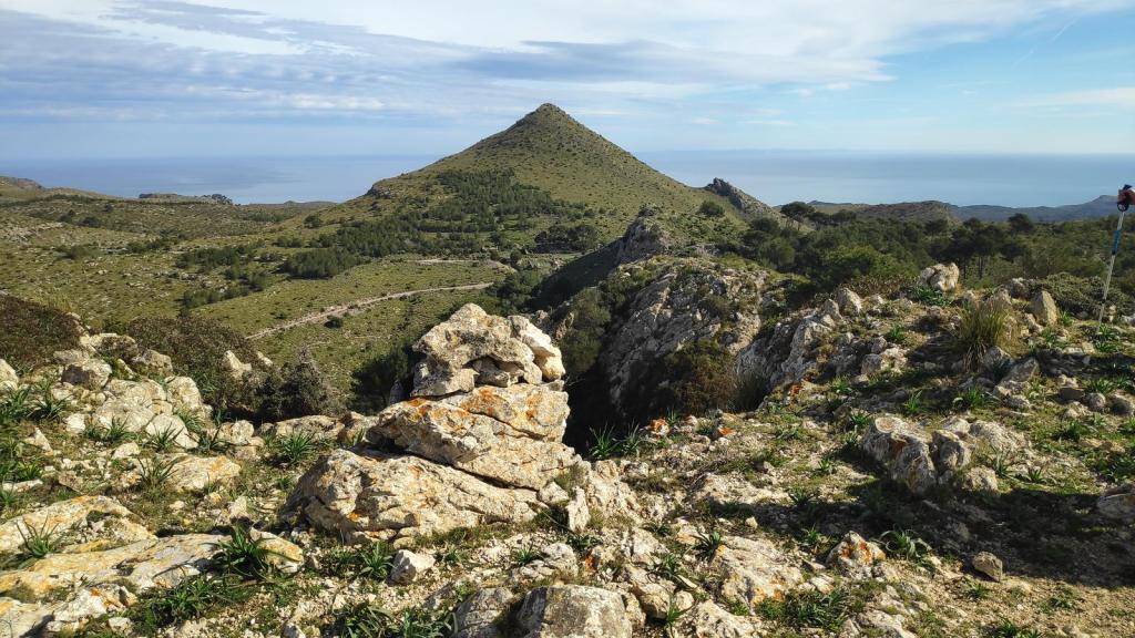 Puig del Porrassar desde s’Alquería Vella - Caminando por Mallorca Vista panorámica del Puig del Porrassar, con su distintiva forma cónica y el paisaje montañoso circundante en el Parque Natural de la Península de Levante.